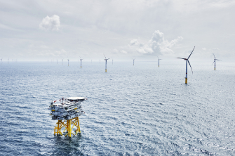 Windräder in einem Offshore-Windpark im Meer bei bewölktem Himmel