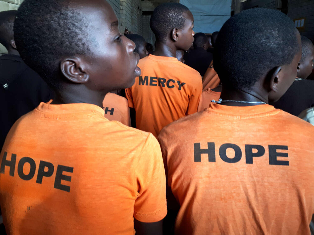 Kinder in orangenen T-Shirts mit den Aufdrucken "Hope" und "Mercy"