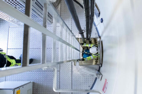 Ein Industriemitarbeiter, der in einer Anlage die Leiter runtersteigt.