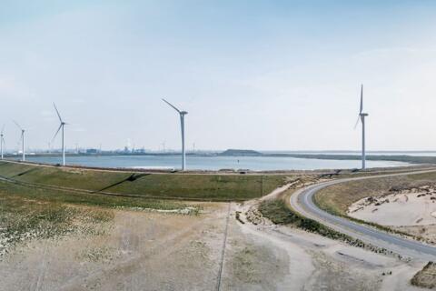 Windräder auf einem Deich am Wasser