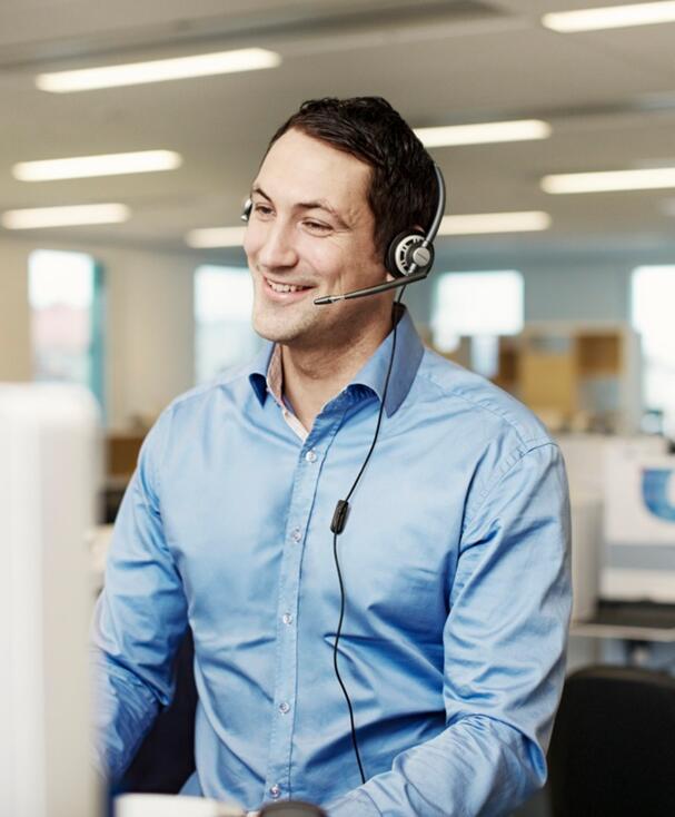 Mann bei der Arbeit am Schreibtisch mit Headset auf 