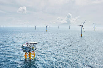 Windräder in einem Offshore-Windpark im Meer bei bewölktem Himmel