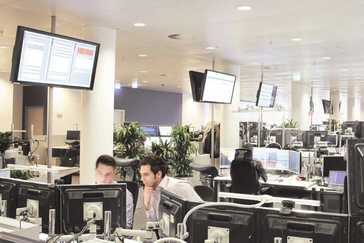 Stagebild Mitarbeiter und Bildschirme im Trading Floor
