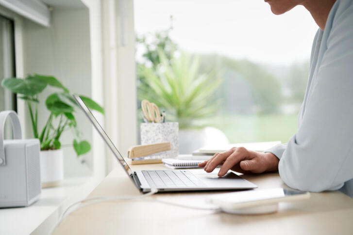 Eine Person sitzt am Laptop in ihrem Büro.
