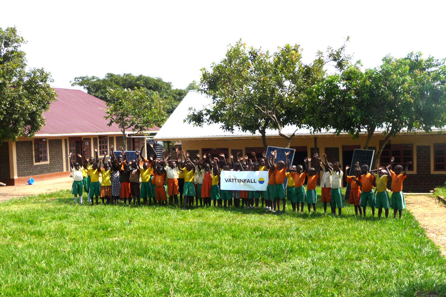 Eine Gruppe Kinder, die einen Vattenfall-Schriftzug in der Hand halten. Im Hintergrund Solaranlagen.