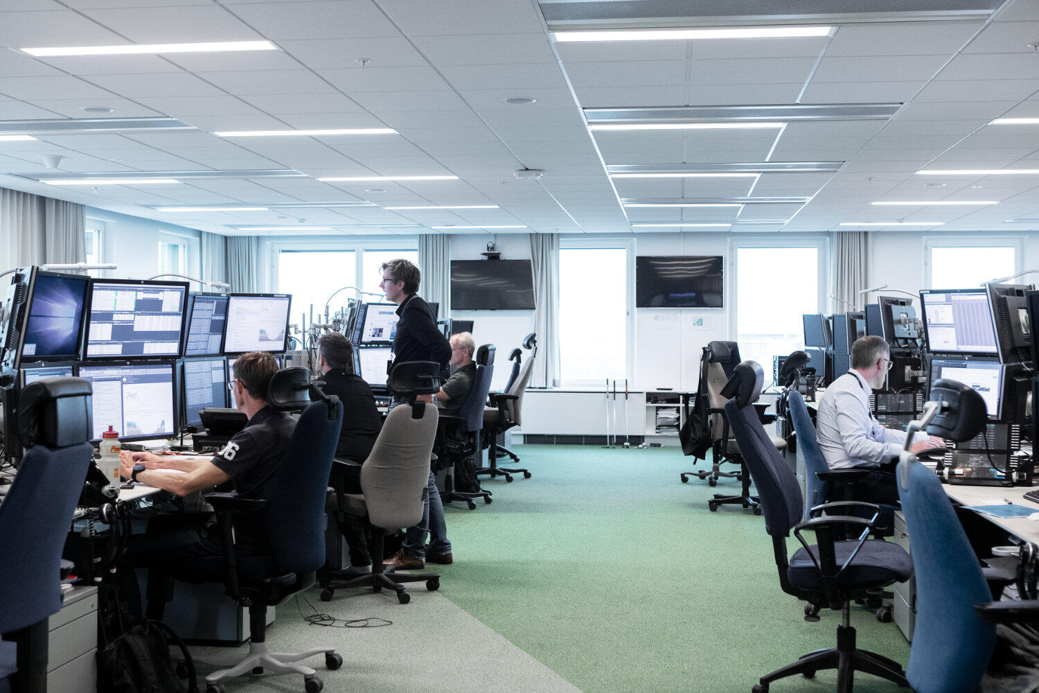 Mehrere Personen in einem Großraumbüro. Alle schauen auf Bildschirme.