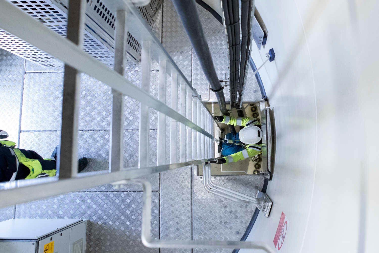 Ein Industriemitarbeiter, der in einer Anlage die Leiter runtersteigt.