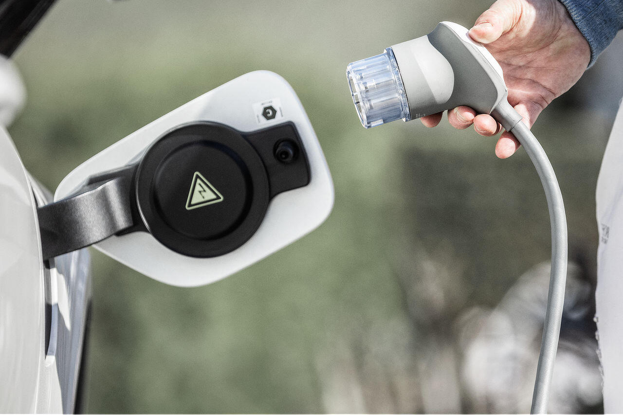 Eine Person steckt einen Ladestecker in ein Elektroauto