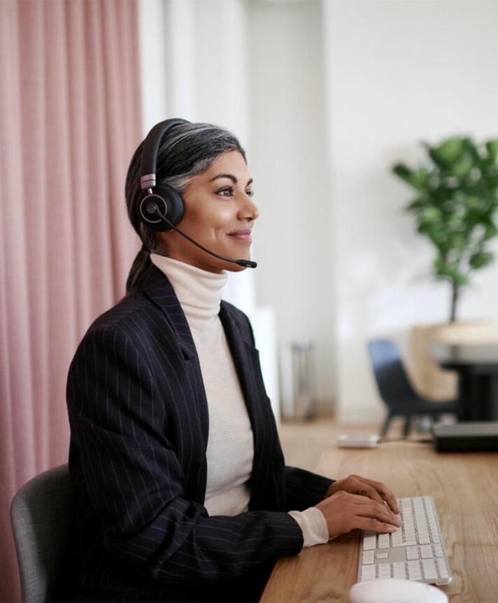 Frau bei der Arbeit am Schreibtisch mit Headset auf