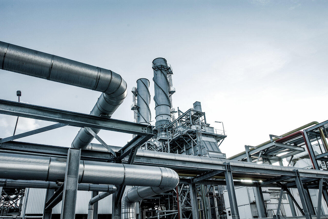 Industrieanlage mit vielen Gasleitungen vor einem blauen Himmel