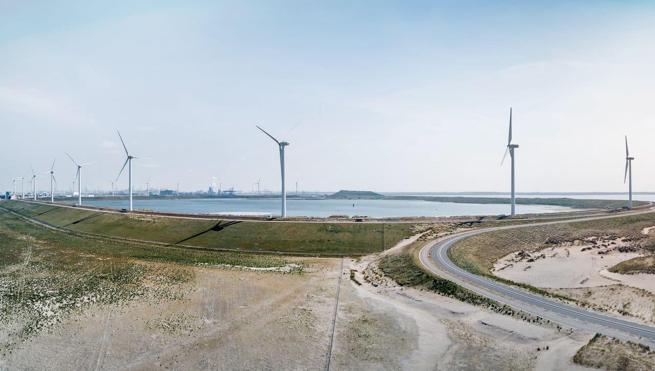 Windräder auf einem Deich am Wasser