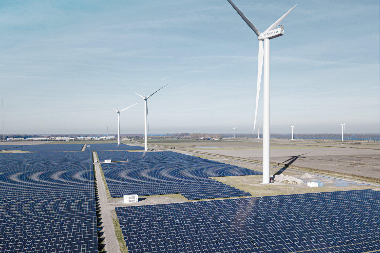 Luftaufnahme eines Hybridparks mit Solarpaneelen und Windrädern.